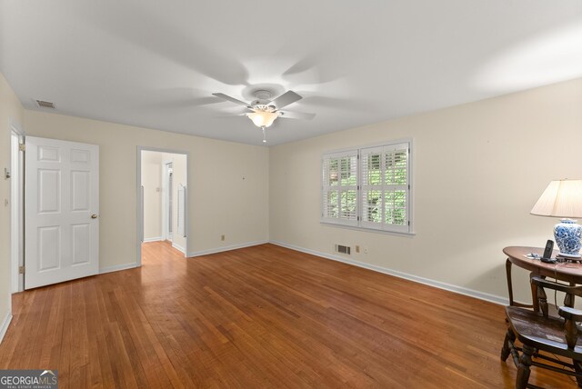 interior space with baseboards, ceiling fan, wood finished floors, and visible vents