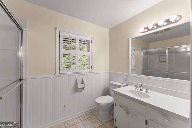 full bath with wainscoting, tile patterned flooring, vanity, toilet, and an enclosed shower