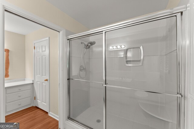 bathroom with wood finished floors and a stall shower
