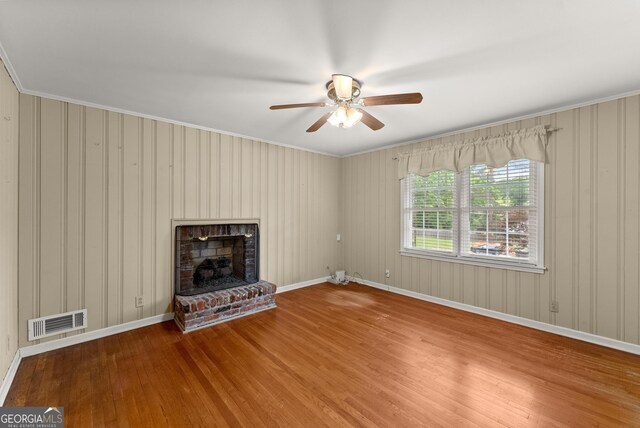 unfurnished living room with visible vents, a ceiling fan, wood finished floors, and ornamental molding