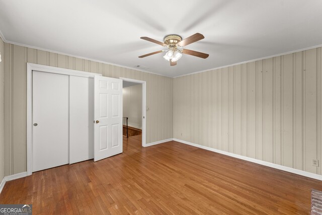 unfurnished bedroom with ornamental molding, a closet, wood finished floors, and visible vents