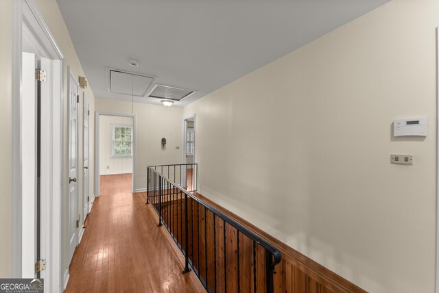corridor with visible vents, attic access, light wood-type flooring, and an upstairs landing