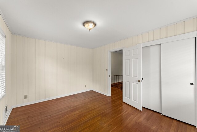unfurnished bedroom with baseboards, a closet, wood finished floors, and visible vents