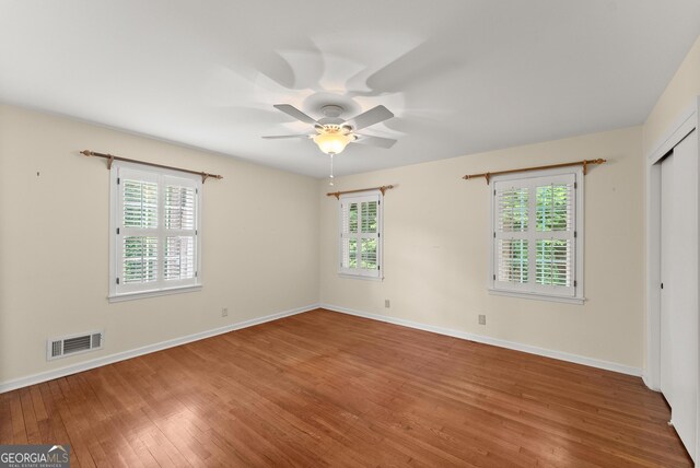 interior space with baseboards, ceiling fan, hardwood / wood-style floors, and visible vents