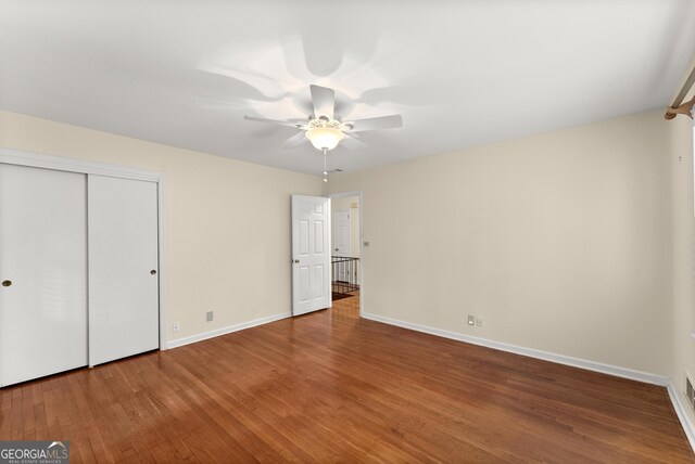 unfurnished bedroom with baseboards, ceiling fan, wood finished floors, and a closet
