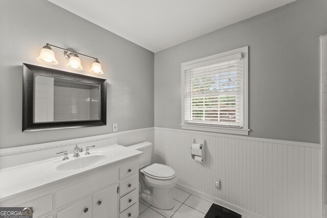 full bathroom with a wainscoted wall, tile patterned flooring, vanity, and toilet