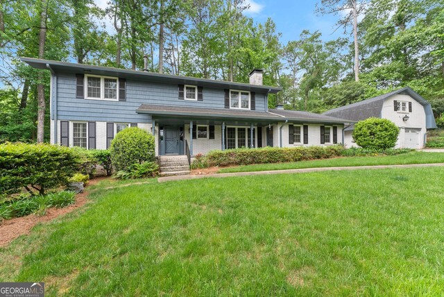view of front facade featuring brick siding, a garage, a chimney, and a front lawn