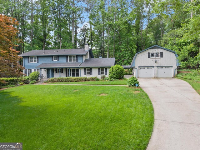 view of front of property featuring a detached garage, covered porch, a chimney, and a front lawn