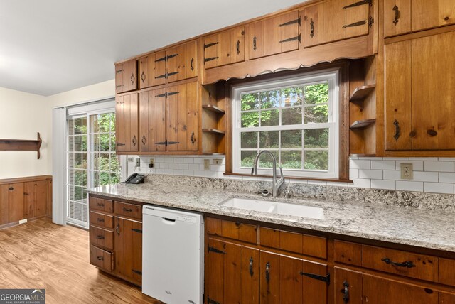 kitchen featuring white dishwasher, tasteful backsplash, open shelves, a sink, and light wood-style flooring