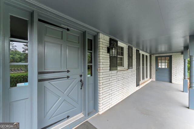 entrance to property featuring a porch and brick siding