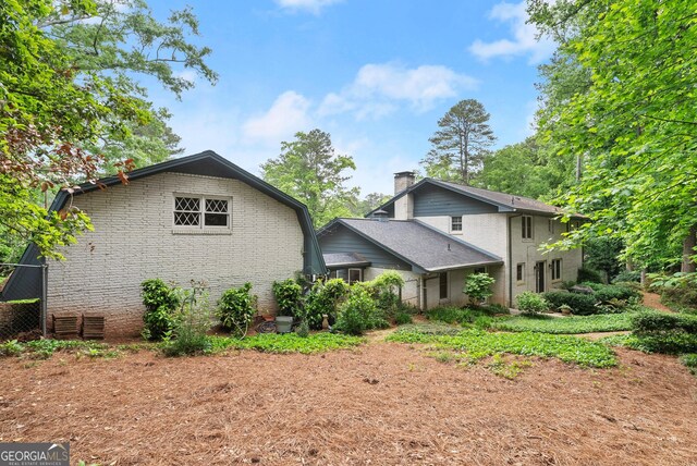 back of property with brick siding and a chimney