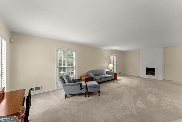 living area featuring a large fireplace, baseboards, light carpet, and visible vents