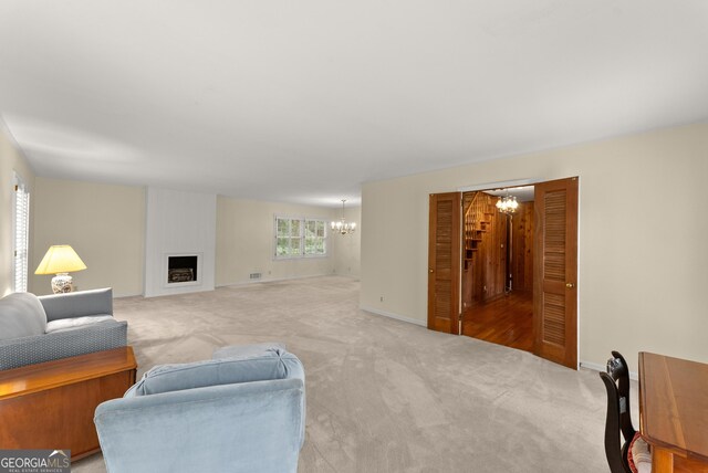 carpeted living room featuring a large fireplace, baseboards, visible vents, and a chandelier