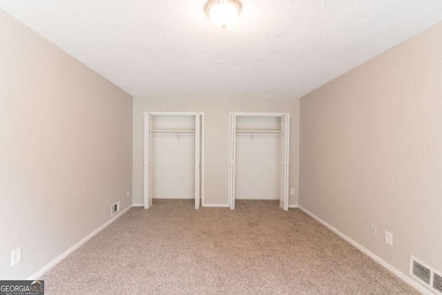 6255 Saddlewood Dr, Lithonia, GA 30058 - unfurnished bedroom with two closets, carpet, and a textured ceiling