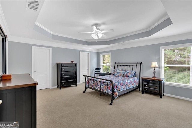 bedroom with a raised ceiling, light colored carpet, crown molding, and multiple windows