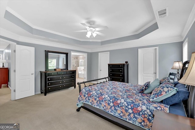 bedroom featuring a tray ceiling, light colored carpet, multiple windows, ornamental molding, and ensuite bathroom