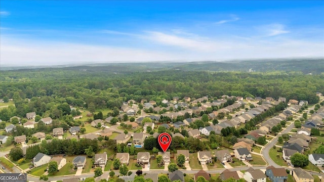 aerial view of property's location featuring a heavily wooded area and nearby suburban area