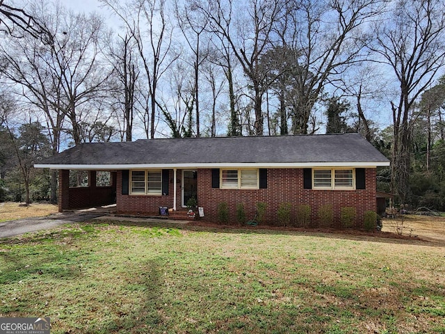 single story home featuring brick siding, an attached carport, driveway, and a front yard