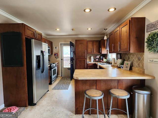 kitchen featuring crown molding, appliances with stainless steel finishes, a sink, light countertops, and a peninsula