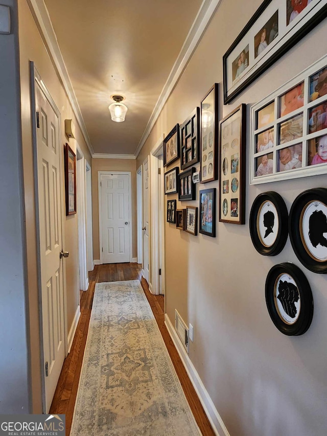 hall with crown molding, baseboards, visible vents, and dark wood-type flooring
