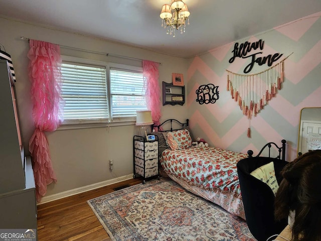 bedroom featuring baseboards, wood finished floors, a notable chandelier, and visible vents