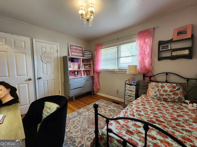 bedroom with baseboards, wood finished floors, and a chandelier