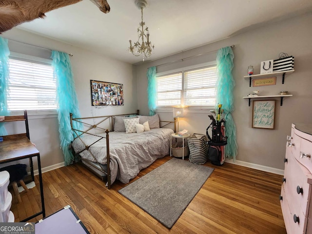 bedroom with baseboards, an inviting chandelier, and wood finished floors