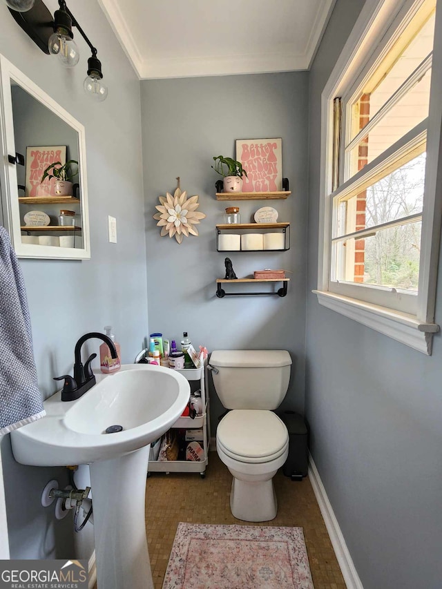 bathroom featuring crown molding, baseboards, and toilet