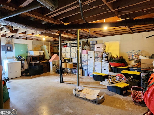 unfinished basement with concrete block wall, electric panel, and washer / clothes dryer