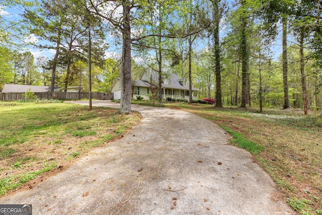 view of front of property featuring fence, curved driveway, and a front yard