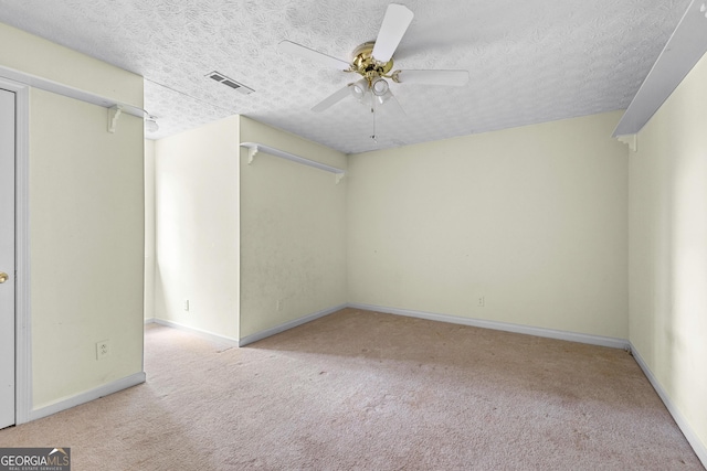 spare room with carpet floors, ceiling fan, a textured ceiling, and visible vents