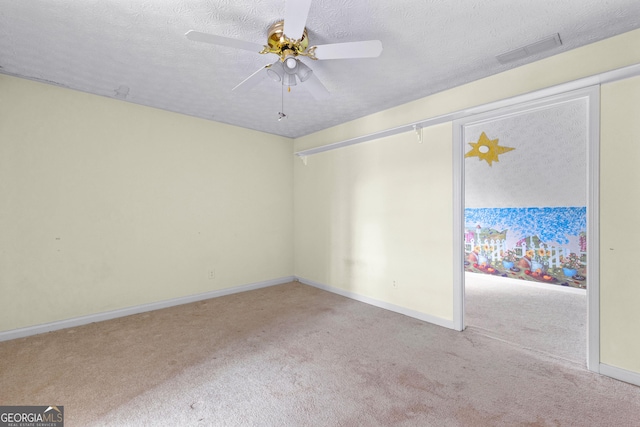 carpeted empty room with a ceiling fan, baseboards, visible vents, and a textured ceiling