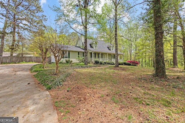 view of front of house featuring covered porch, fence, and concrete driveway
