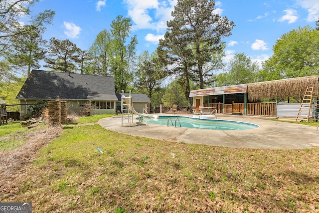 pool featuring a yard, a water slide, and a patio area