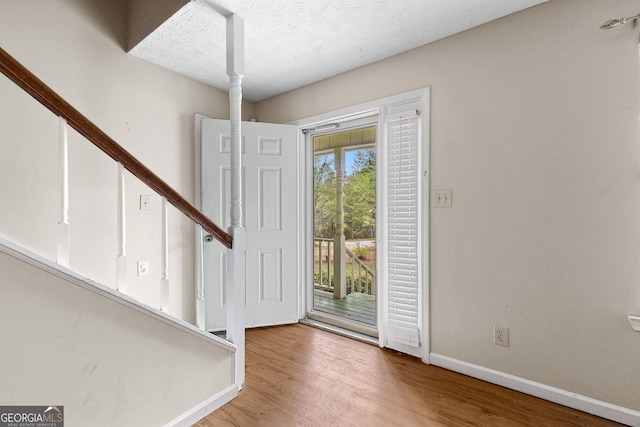 entryway featuring a textured ceiling, baseboards, and wood finished floors