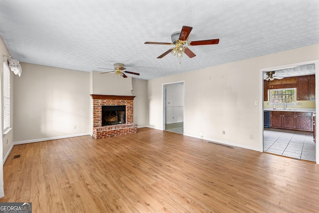 unfurnished living room featuring light wood-style floors, a textured ceiling, ceiling fan, and visible vents