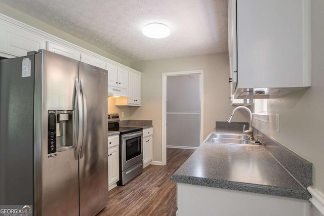 5028 Nichols Dr, Flowery Branch, GA 30542 - kitchen with appliances with stainless steel finishes, white cabinetry, dark wood finished floors, under cabinet range hood, and a textured ceiling