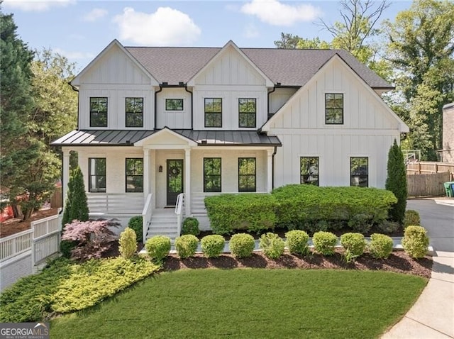 modern inspired farmhouse with board and batten siding, fence, a front yard, and a standing seam roof