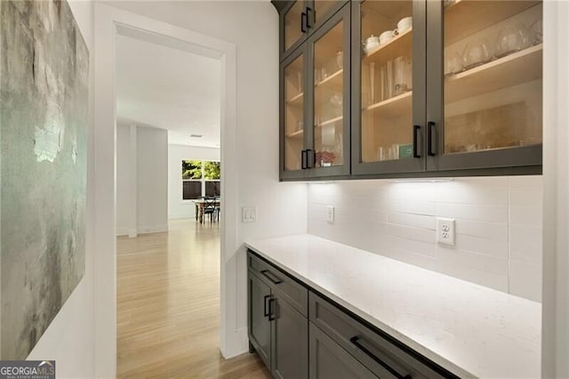 bar featuring decorative backsplash and light wood-type flooring