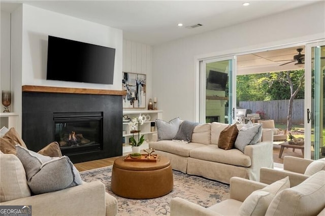 living area with wood finished floors, visible vents, recessed lighting, ceiling fan, and a glass covered fireplace