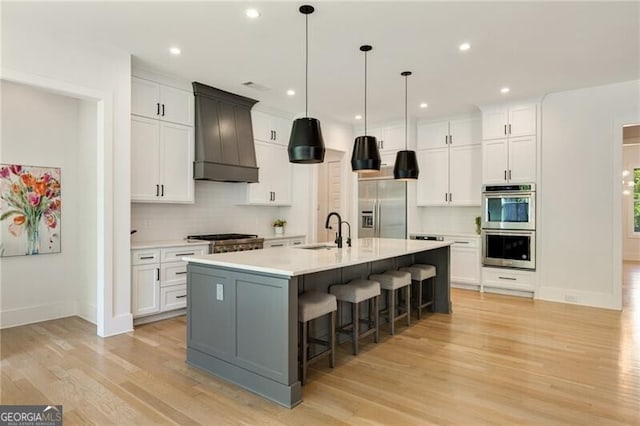 kitchen featuring premium range hood, stainless steel appliances, backsplash, and a sink