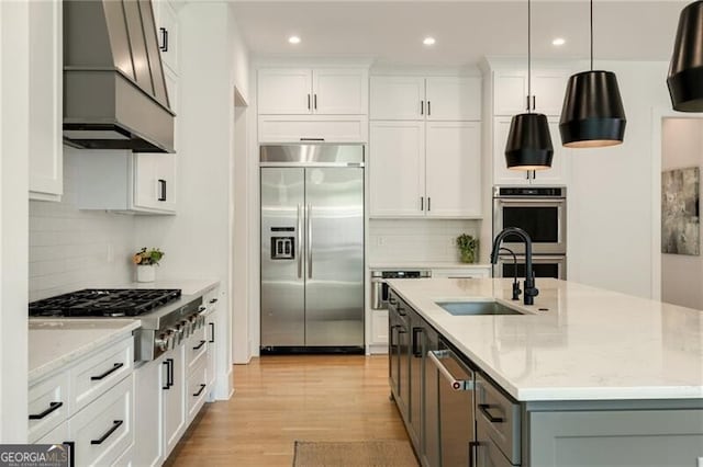 kitchen with a sink, stainless steel appliances, white cabinetry, premium range hood, and recessed lighting