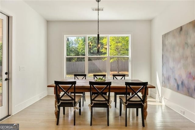dining room with baseboards, a notable chandelier, visible vents, and wood finished floors
