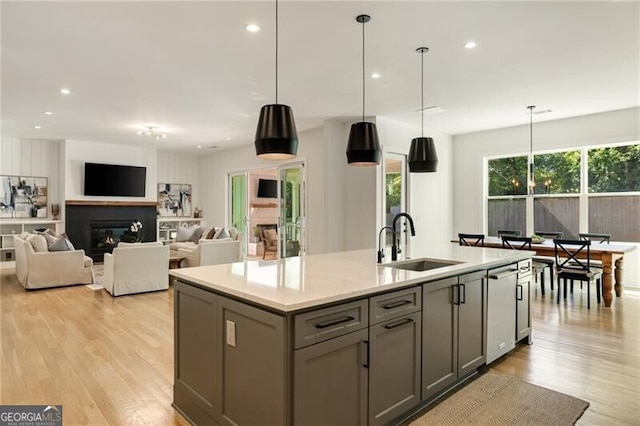 kitchen featuring gray cabinets, light wood-style floors, a sink, and dishwasher