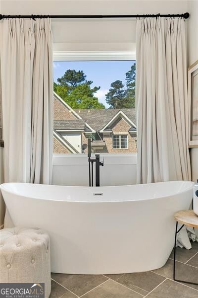 bathroom featuring tile patterned flooring and a freestanding tub