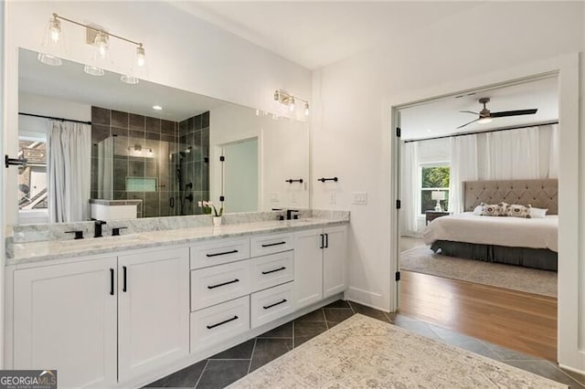 ensuite bathroom with double vanity, a sink, tile patterned floors, a shower stall, and ceiling fan