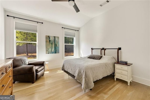 bedroom with lofted ceiling, light wood-type flooring, visible vents, a ceiling fan, and baseboards