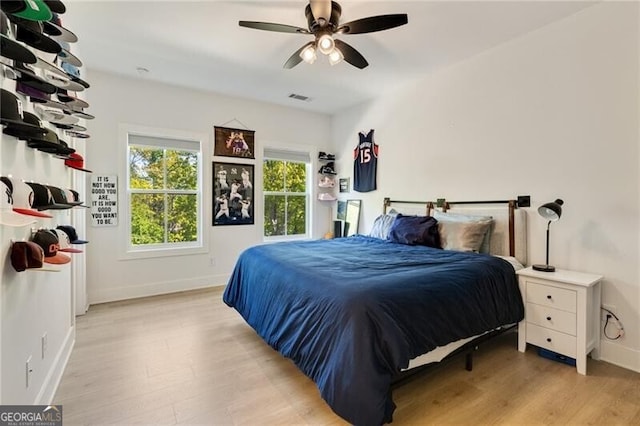 bedroom featuring light wood finished floors, visible vents, baseboards, and a ceiling fan
