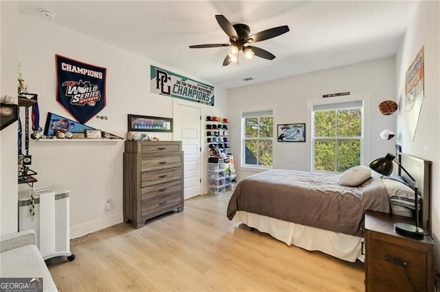 bedroom with a ceiling fan, baseboards, light wood-style flooring, and visible vents