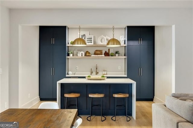 bar with a sink, baseboards, and light wood-type flooring